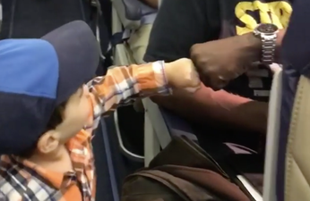 Adorable toddler fist bumping his way onto a flight will make your day