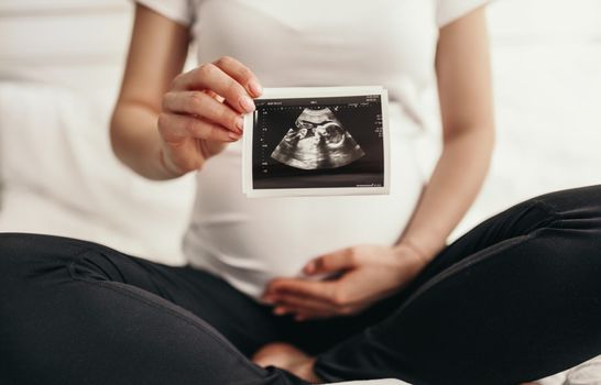 Pregnant woman holding sonogram picture