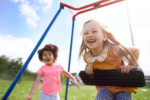 Two kids playing together on swings